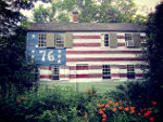 Old wooden house in the USA with American flag painting